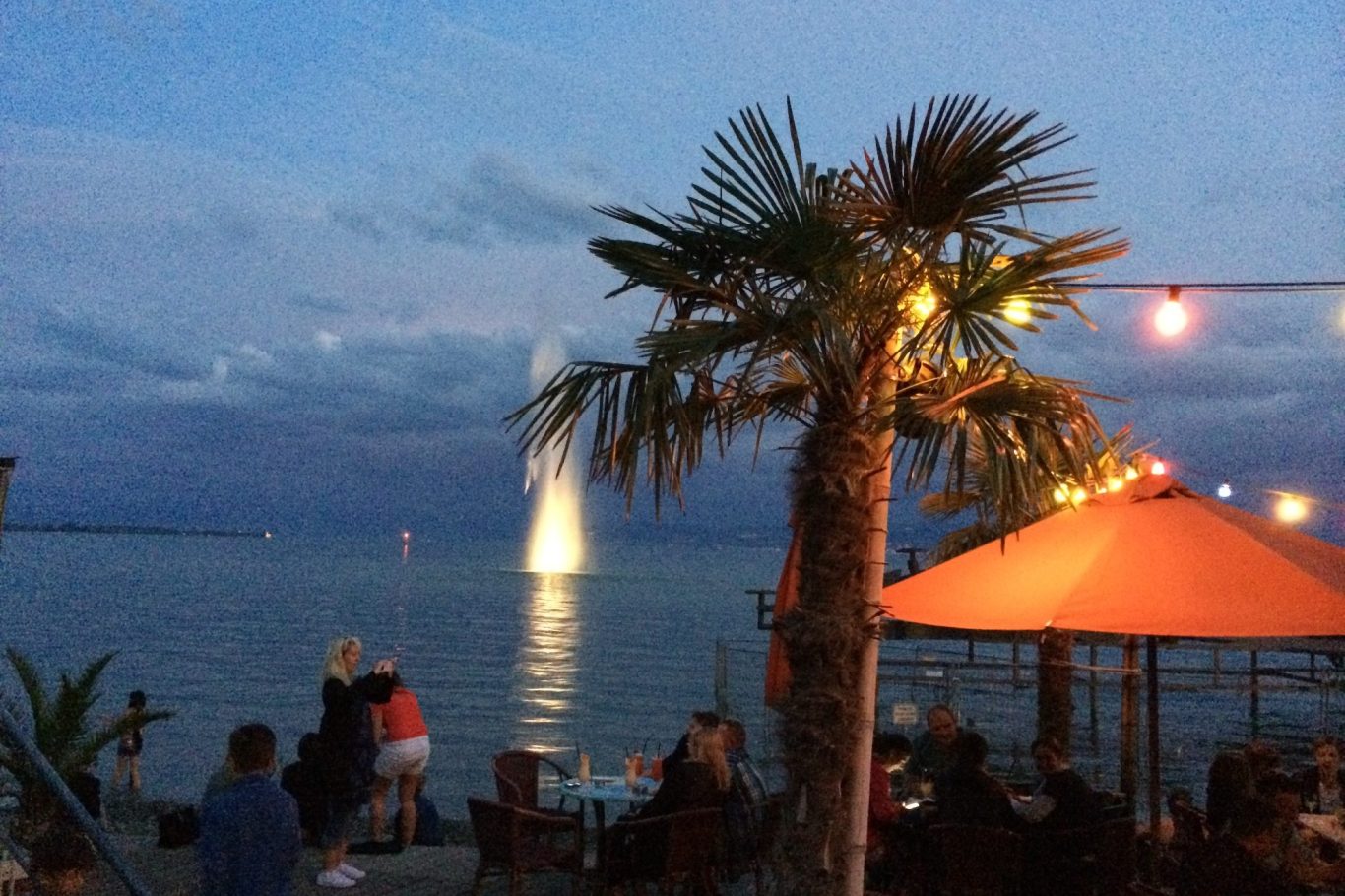 Segelboot auf ruhigem Wasser mit bergiger Küstenlinie im Hintergrund.